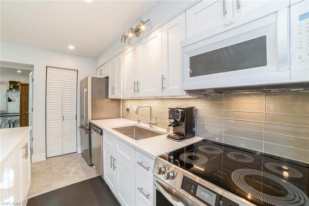 Kitchen featuring stainless steel appliances, white cabinets, decorative backsplash, and recessed lighting