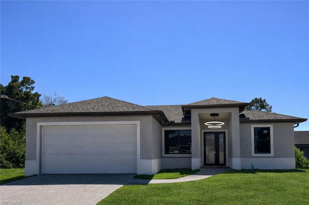 Prairie-style house featuring a front lawn, stucco siding, driveway, and an attached garage