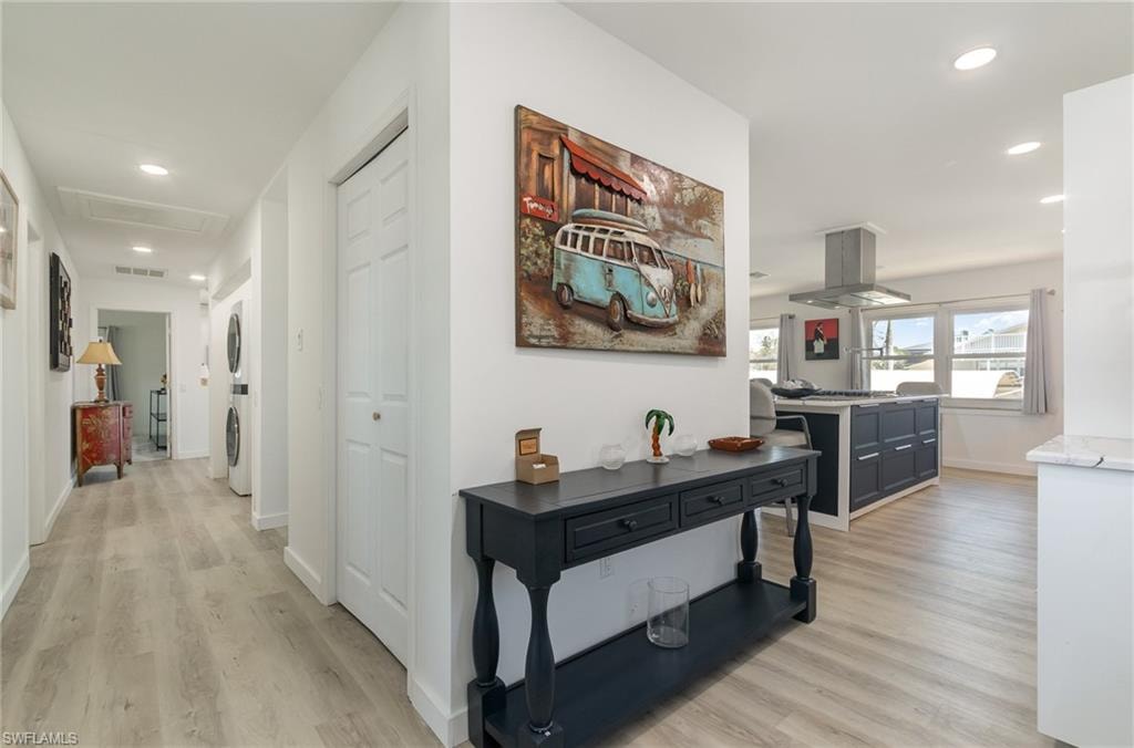 Corridor with recessed lighting, light wood finished floors, attic access, and stacked washer / drying machine