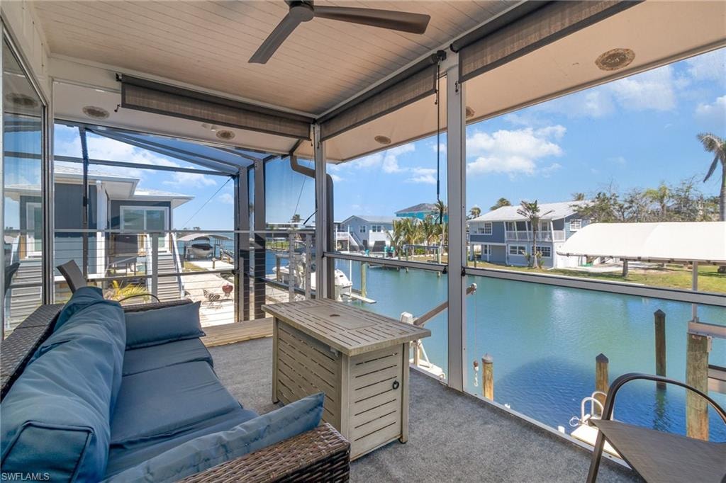 Sunroom / solarium featuring a water view, ceiling fan, and a residential view