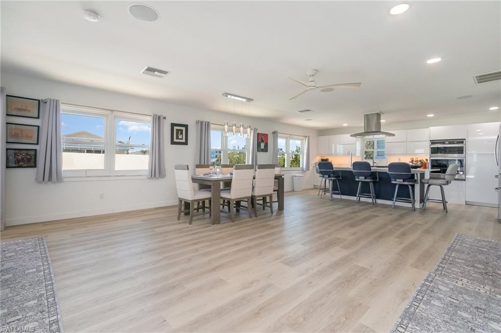Dining space with healthy amount of natural light, ceiling fan, light wood-type flooring, and recessed lighting