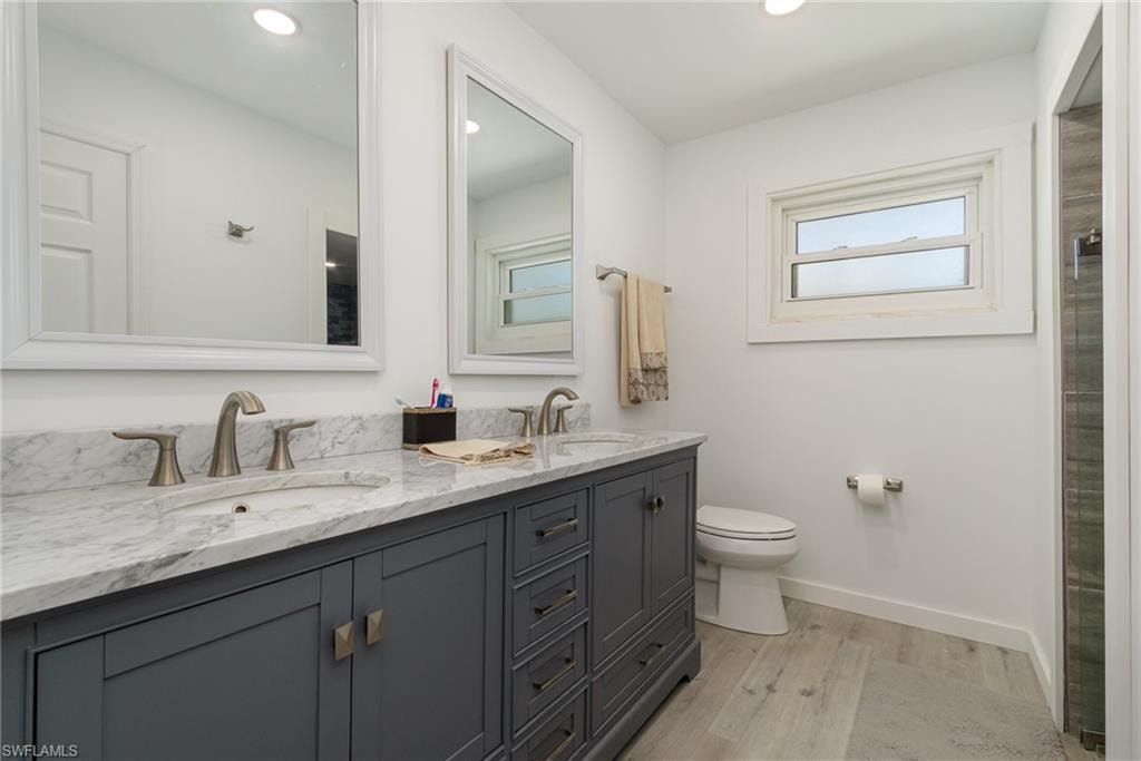 Bathroom featuring light wood-style flooring, double vanity, a shower, and recessed lighting