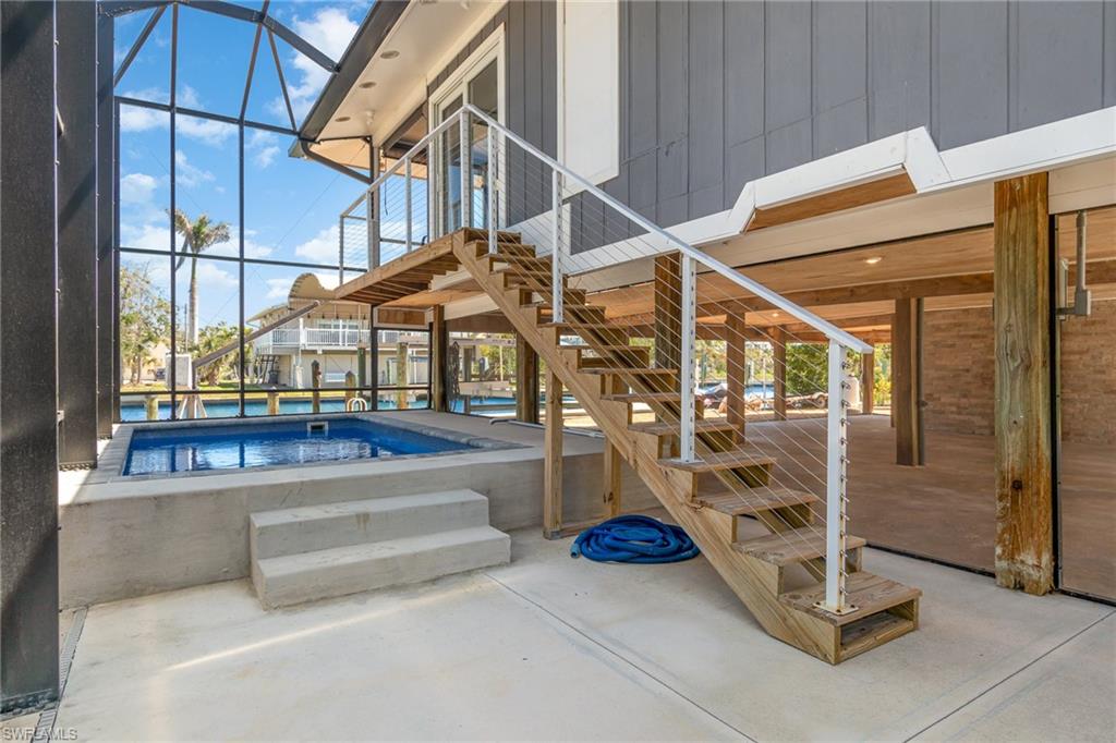 View of patio with stairs, glass enclosure, a sunroom, and an outdoor pool