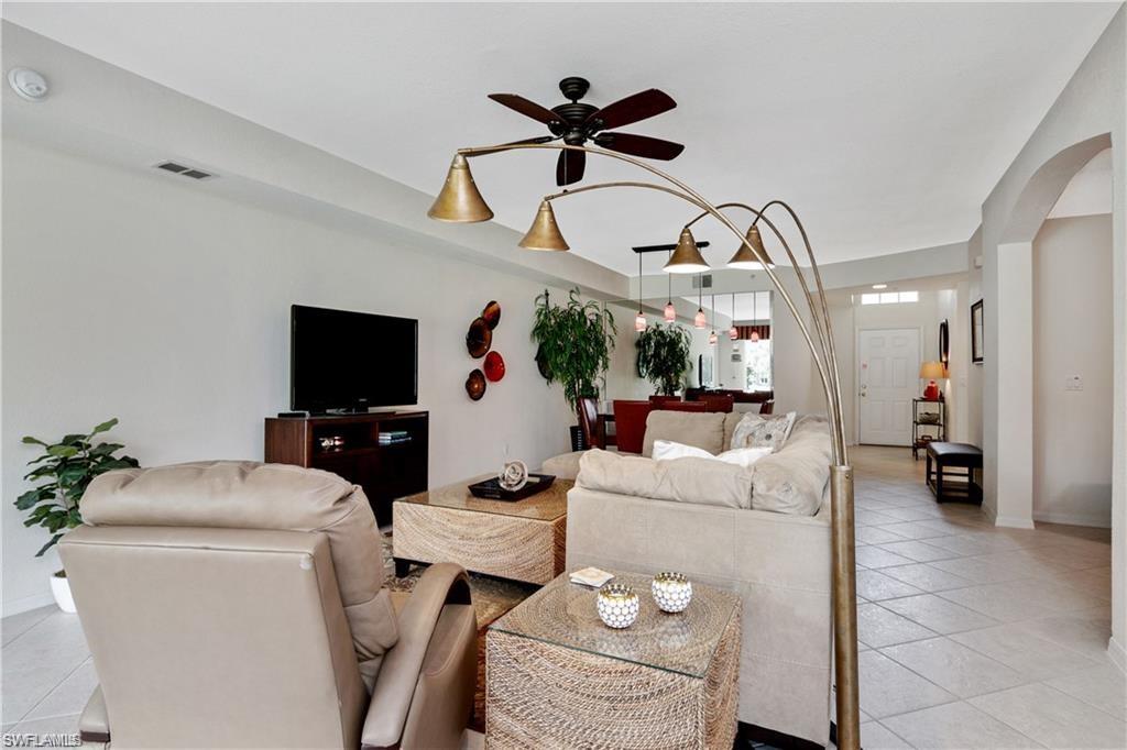 Living room featuring light tile patterned floors, ceiling fan, and arched walkways