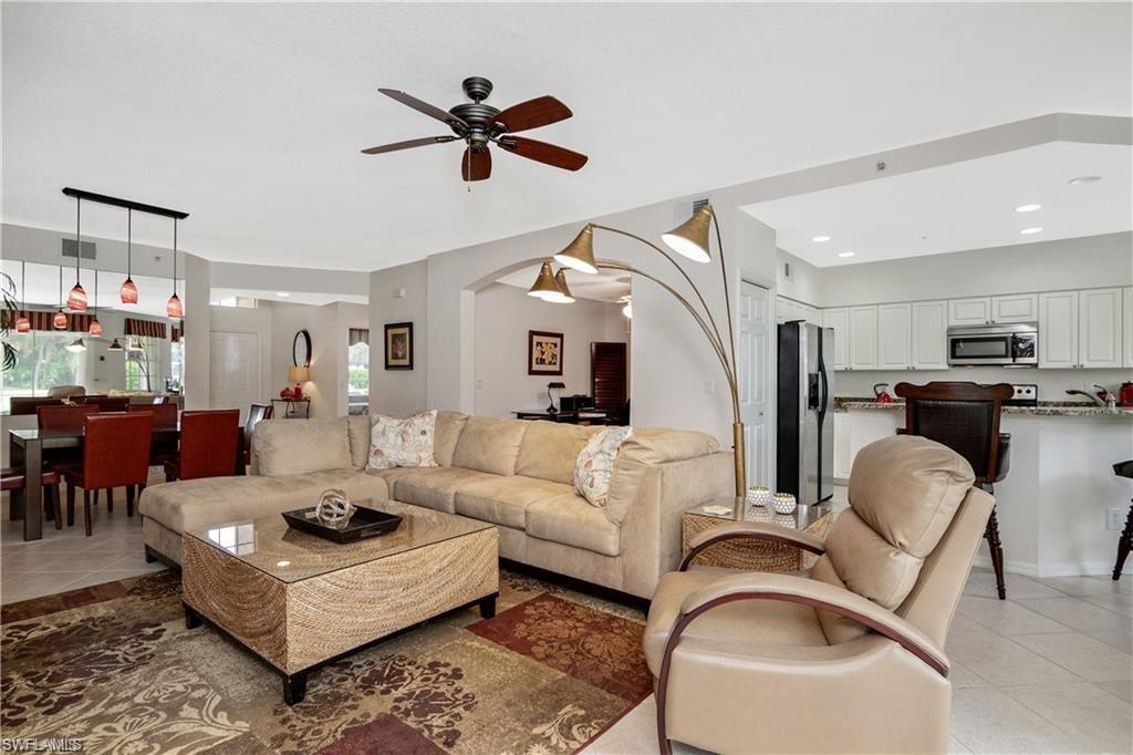 Living room featuring light tile patterned floors, ceiling fan, arched walkways, and recessed lighting