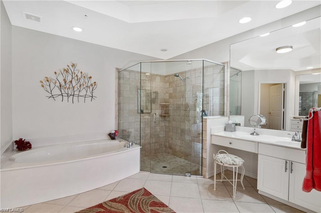 Bathroom with a bath, vanity, a shower stall, a raised ceiling, and light tile patterned floors