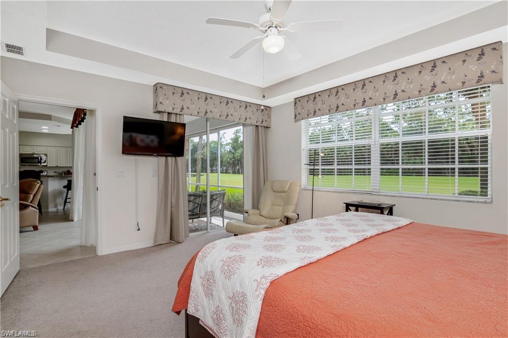 Bedroom featuring access to outside, carpet floors, a tray ceiling, and ceiling fan