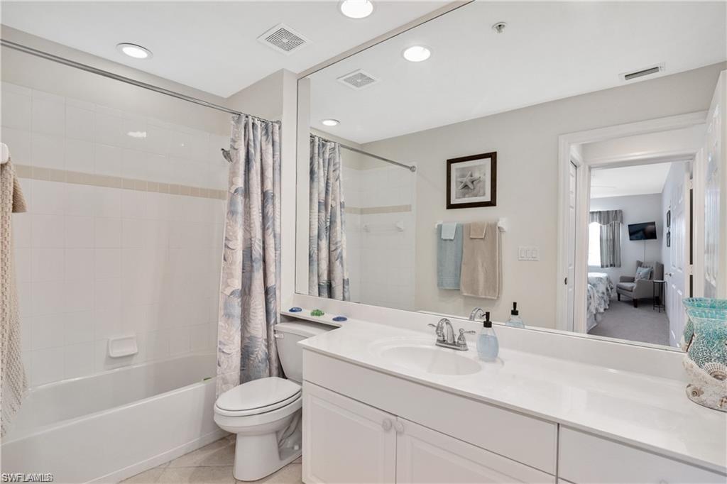 Ensuite bathroom with vanity, shower / tub combo with curtain, and light tile patterned floors