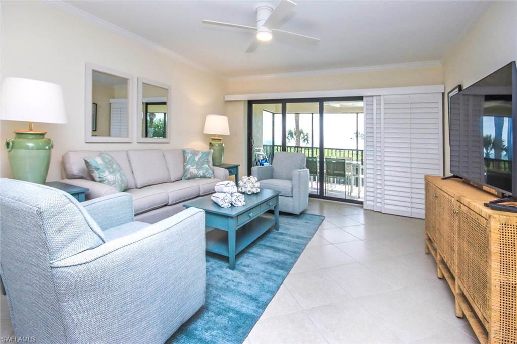 Living area with crown molding, light tile patterned floors, and ceiling fan