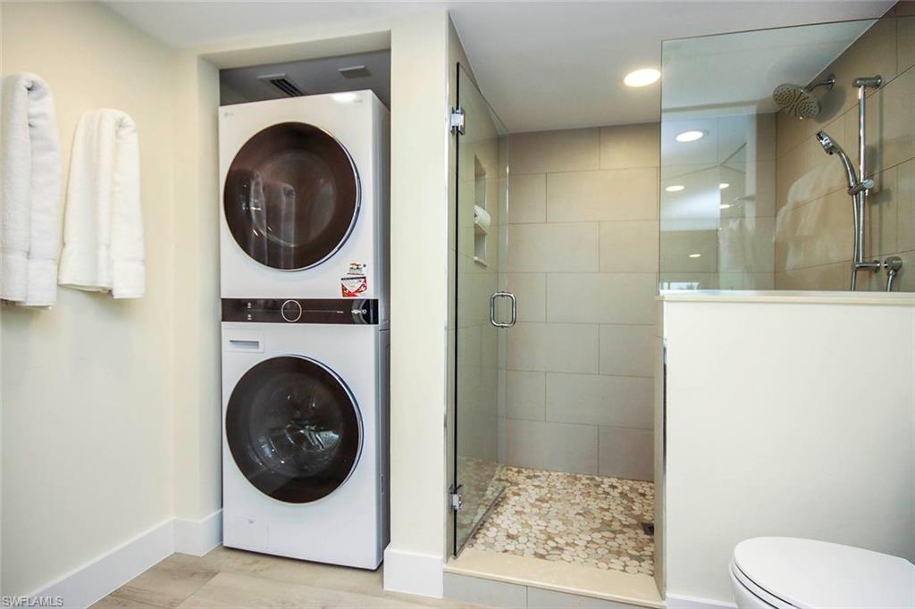 Full bathroom featuring estacked washer and dryer, a stall shower, recessed lighting, and light wood finished floors