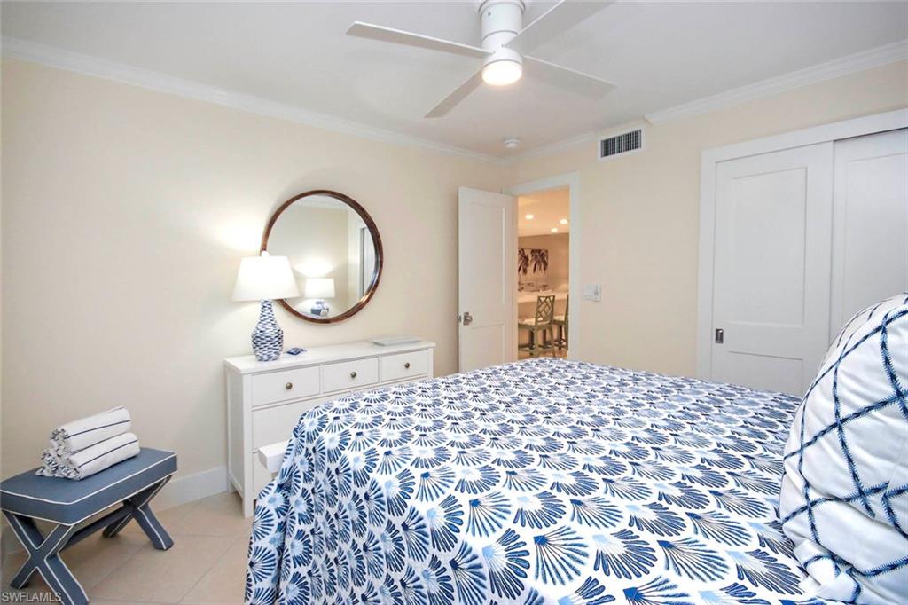 Bedroom with ornamental molding, light tile patterned floors, ceiling fan, and a closet