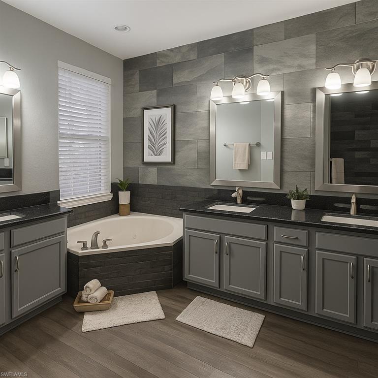 Virtually staged athroom featuring double vanity, a whirlpool tub, tile walls, and dark wood-type flooring