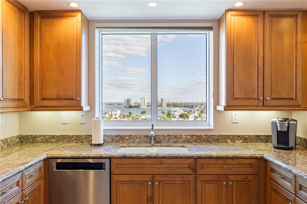 Kitchen featuring brown cabinetry, stainless steel dishwasher, light stone counters, a view of city, and recessed lighting