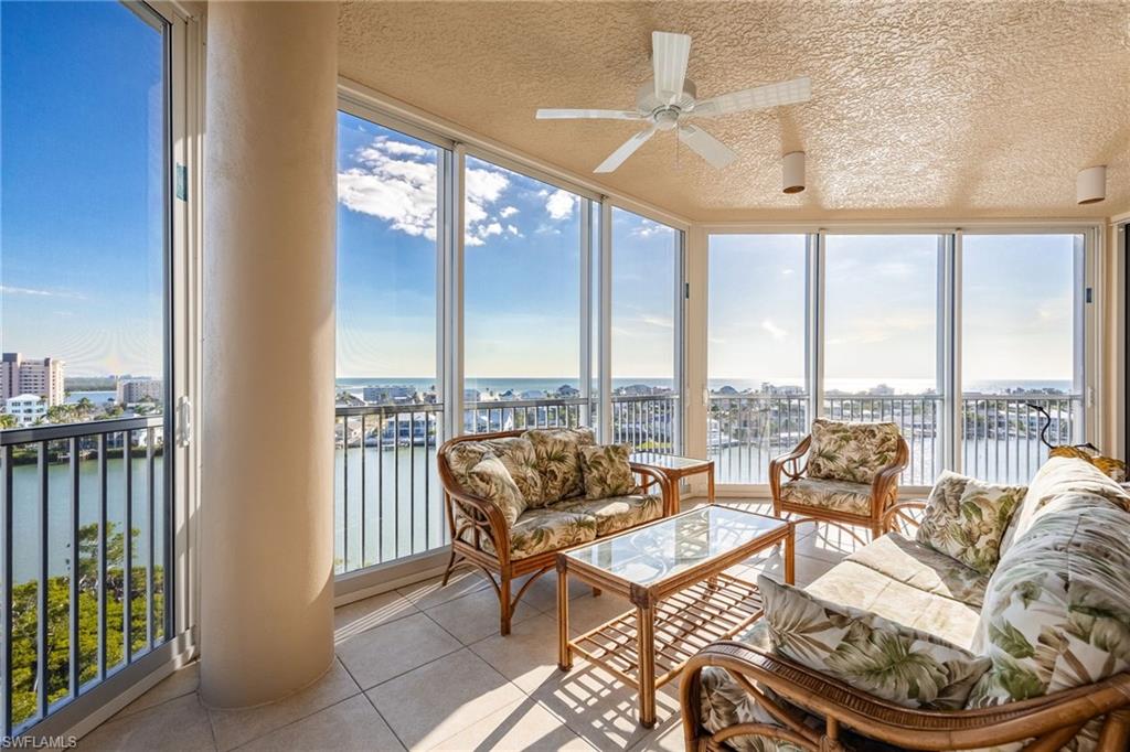 Sunroom / solarium featuring expansive windows, a water view, a textured ceiling, and tile patterned floors