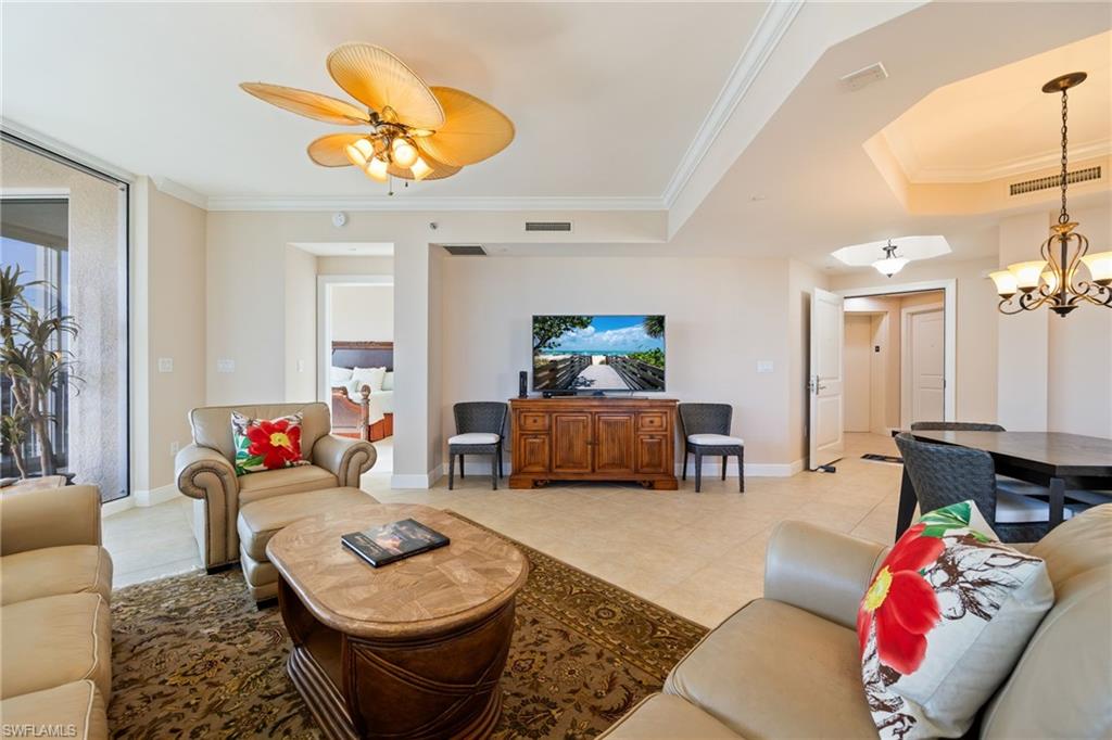 Living room with ornamental molding, light tile patterned floors, a chandelier, and a ceiling fan