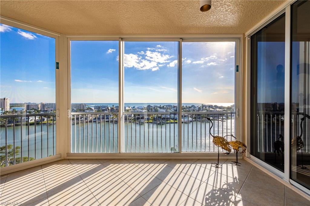 Unfurnished sunroom featuring expansive windows, a water view, and tile patterned floors