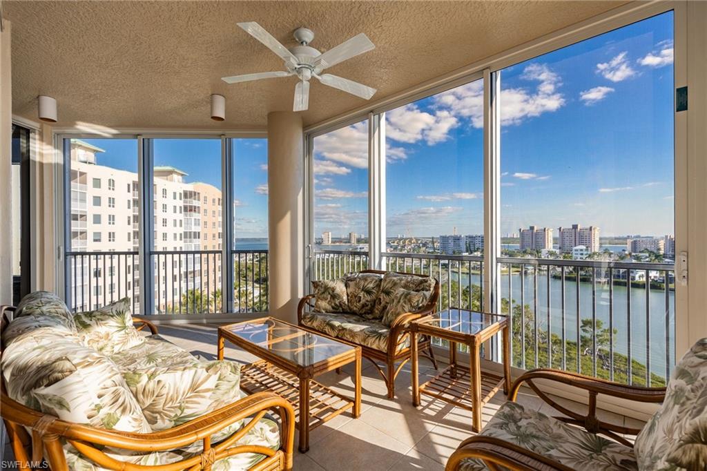 Sunroom featuring a water view, a city view, a textured ceiling, expansive windows, and tile patterned flooring