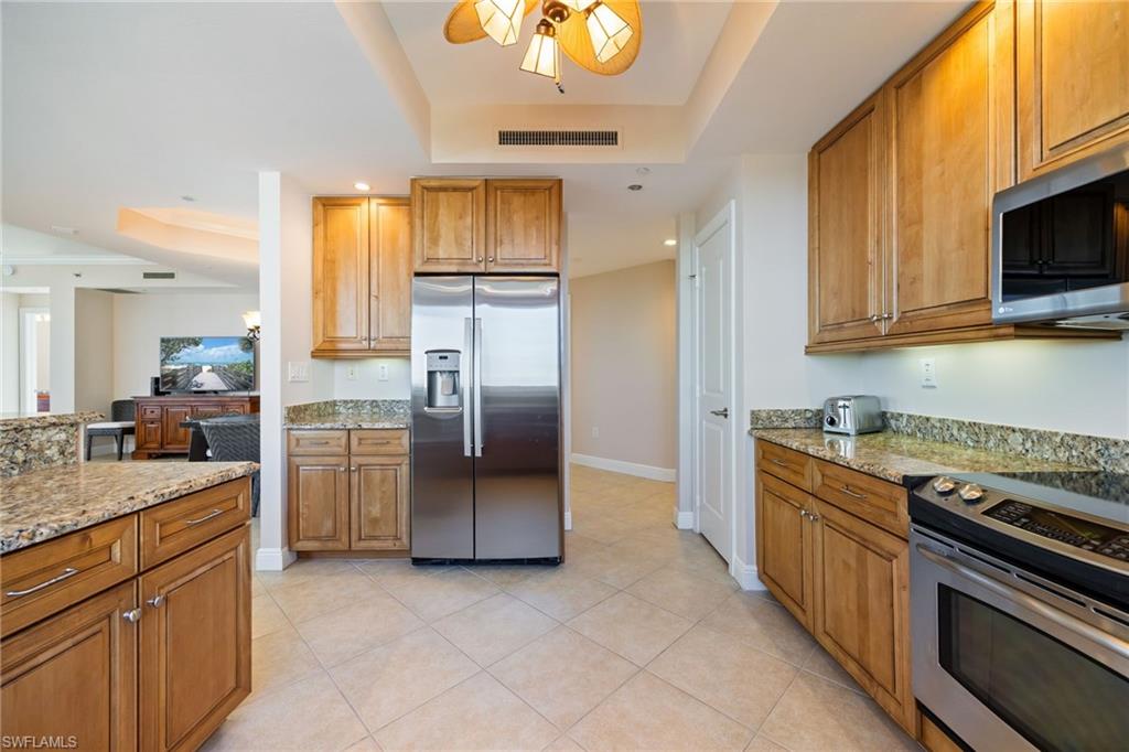 Kitchen with a raised ceiling, appliances with stainless steel finishes, brown cabinets, and recessed lighting