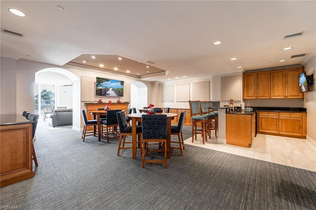 Community Dining space featuring arched walkways, a raised ceiling, recessed lighting, ornamental molding, and light colored carpet