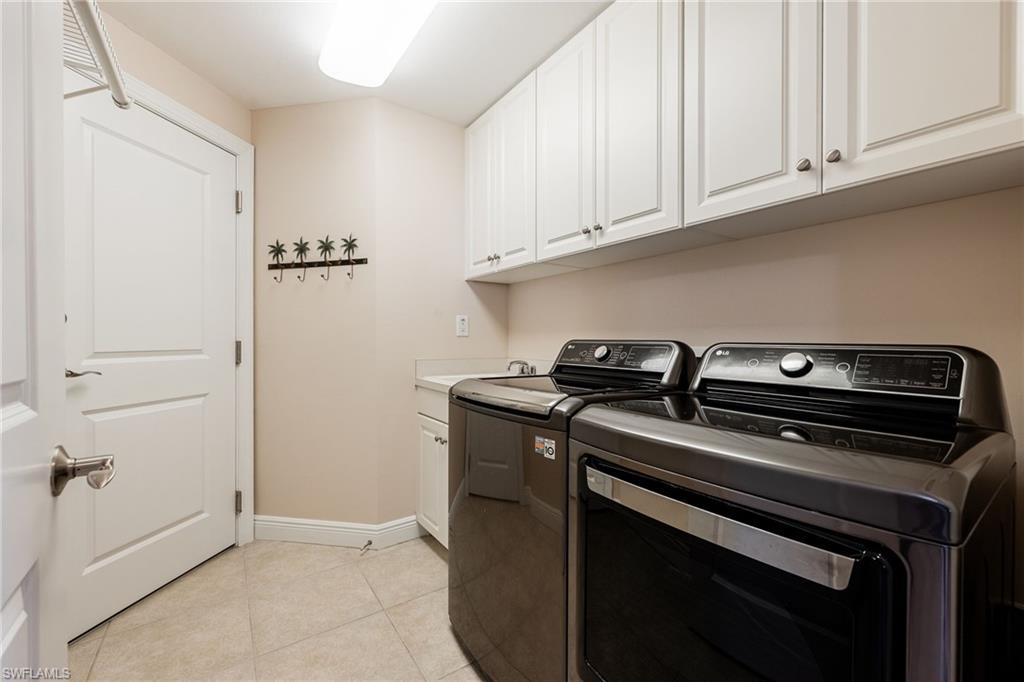 Laundry room featuring washing machine and clothes dryer, light tile patterned flooring, and cabinet space