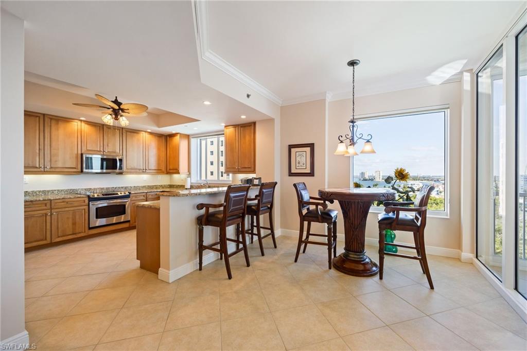Kitchen with a breakfast bar, hanging light fixtures, a peninsula, ornamental molding, and stainless steel appliances