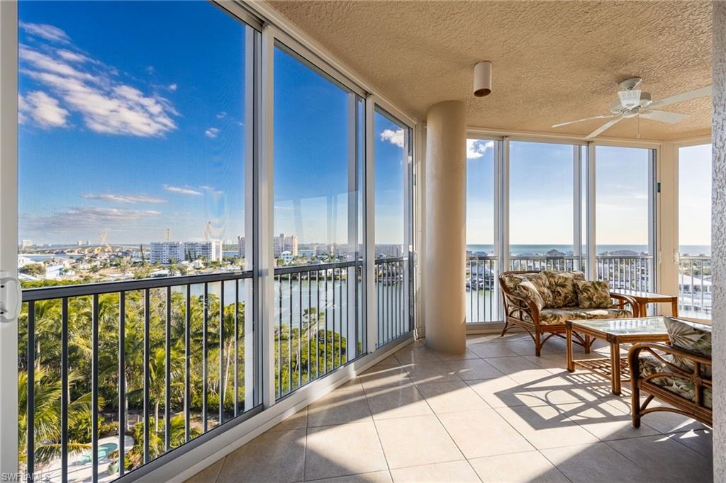 Sunroom with a wall of windows, a water view, tile patterned floors, and a textured ceiling