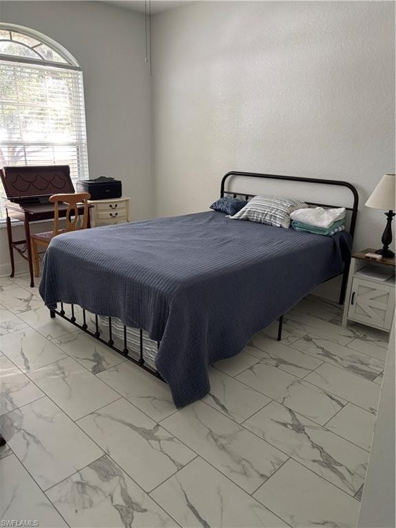 Bedroom featuring light marble finish floors