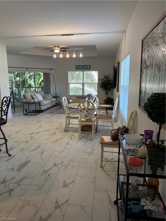 Dining room featuring light marble flooring, plenty of natural light, and a ceiling fan