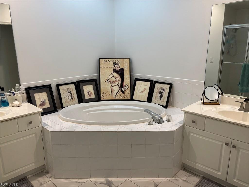 Full bathroom with two vanities, a bath, and a shower stall