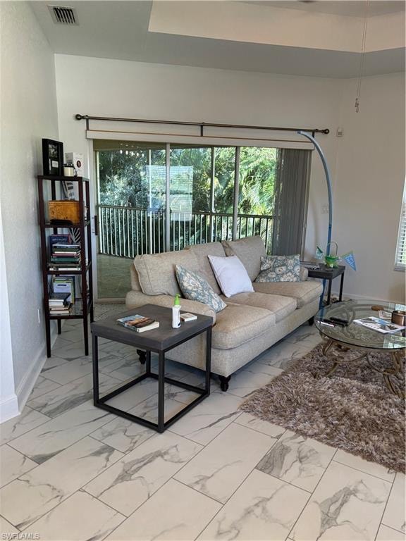 Living room featuring baseboards and light marble finish floors