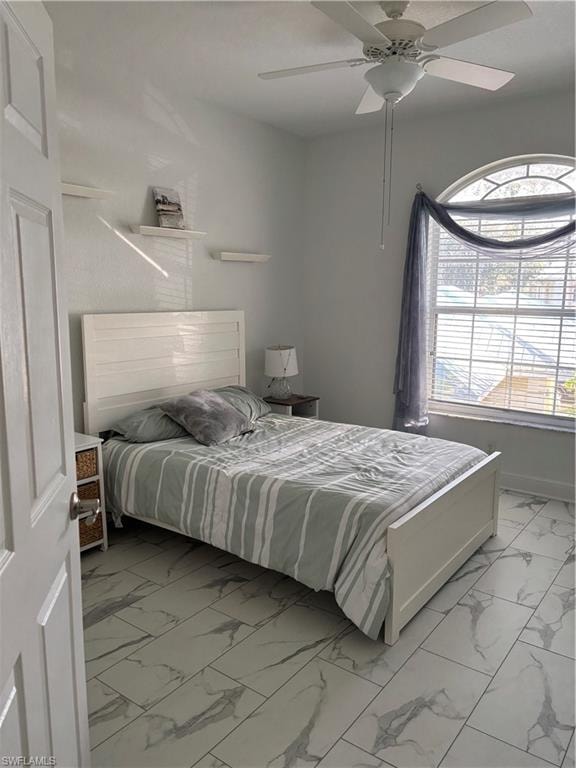 Bedroom with light marble finish floors and ceiling fan