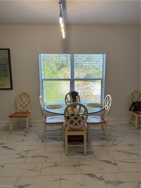 Dining space with light marble finish floors and baseboards
