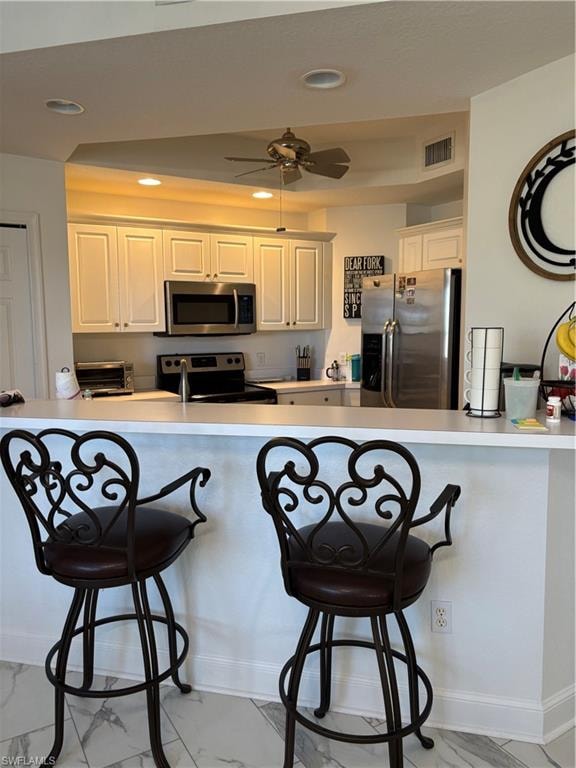 Kitchen with a kitchen breakfast bar, fridge, light countertops, light marble finish flooring, and recessed lighting