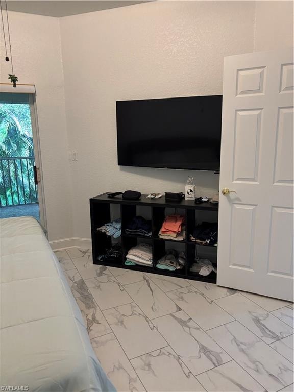 Bedroom featuring light marble finish floors and access to exterior