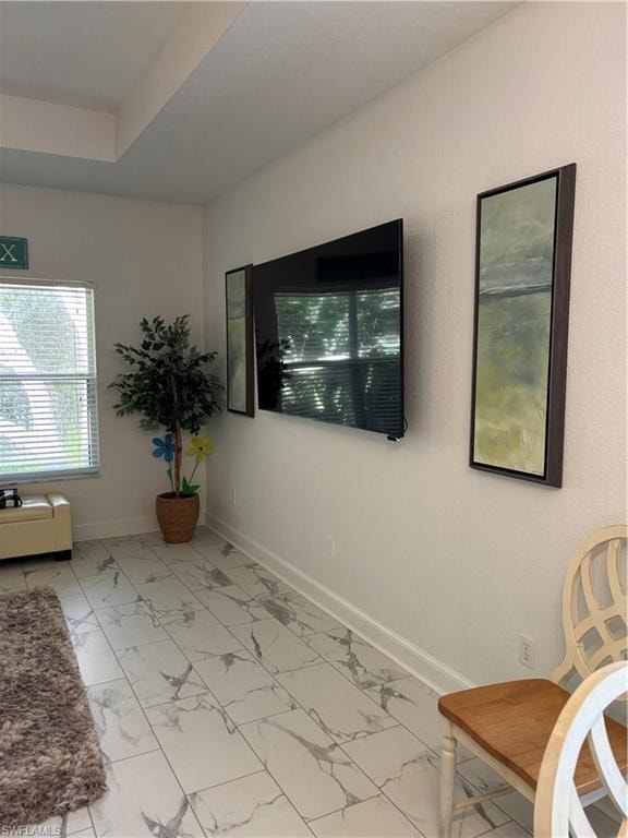 Living area featuring light marble finish floors and a raised ceiling