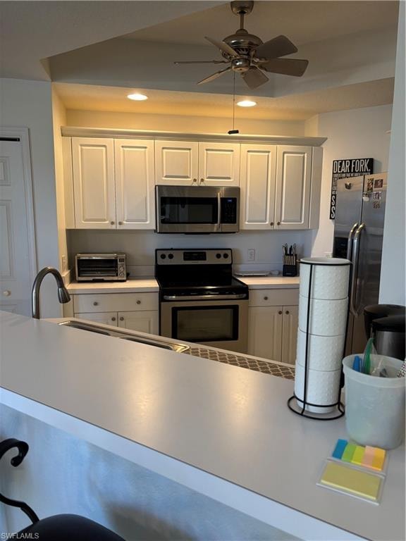 Kitchen featuring stainless steel appliances, white cabinetry, light countertops, a ceiling fan, and recessed lighting