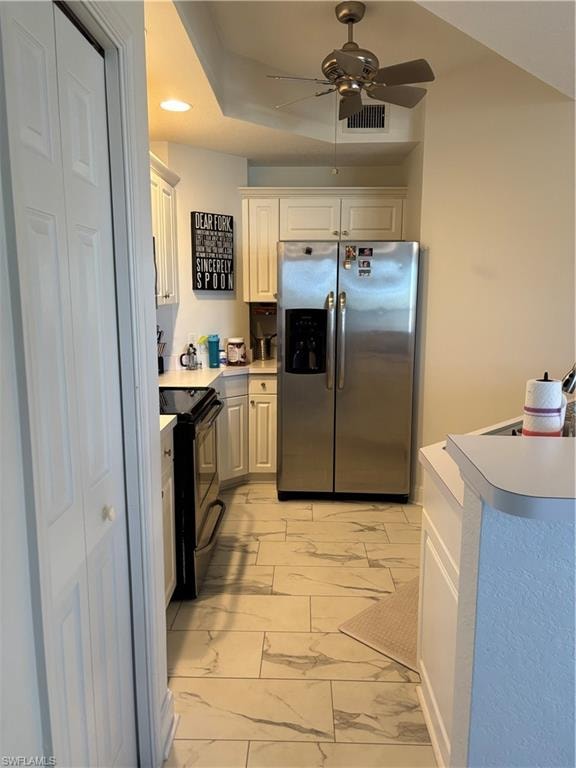 Kitchen featuring refrigerator, stove, light countertops, light marble finish floors, and ceiling fan