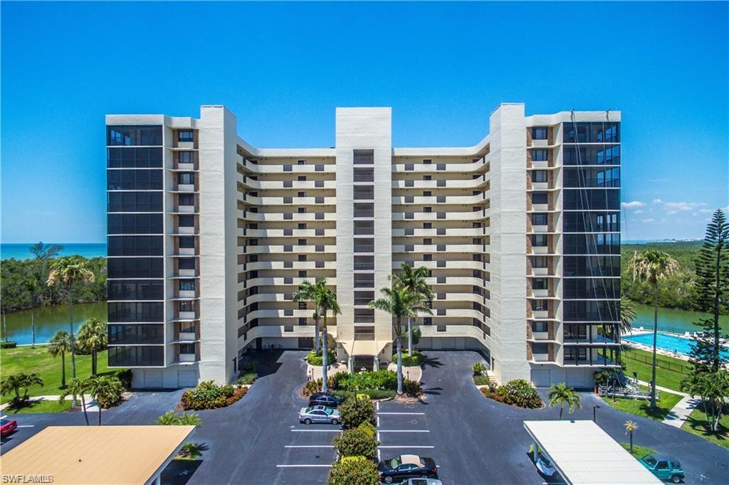 View of apartment building / complex featuring a water view and uncovered parking