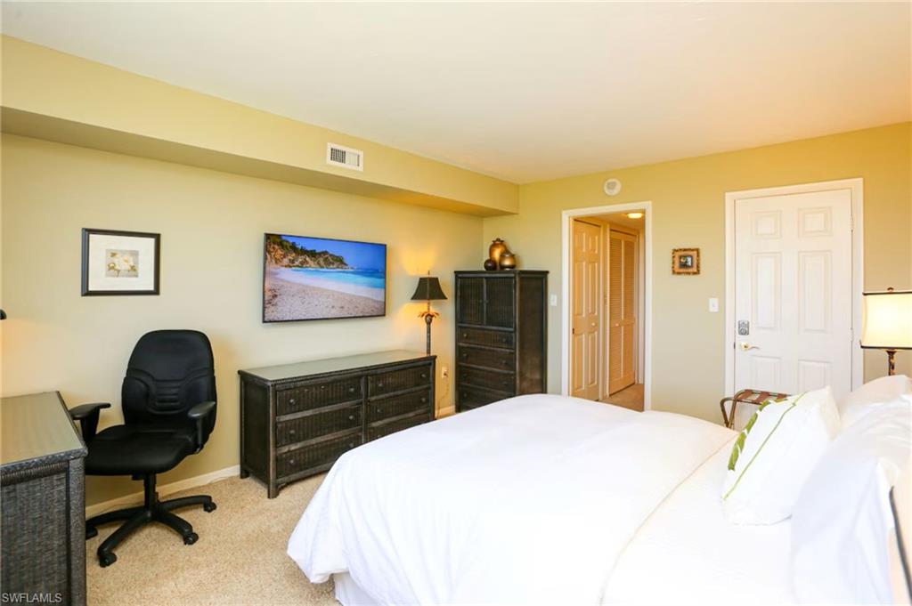 Bedroom with light colored carpet, a closet, and a desk