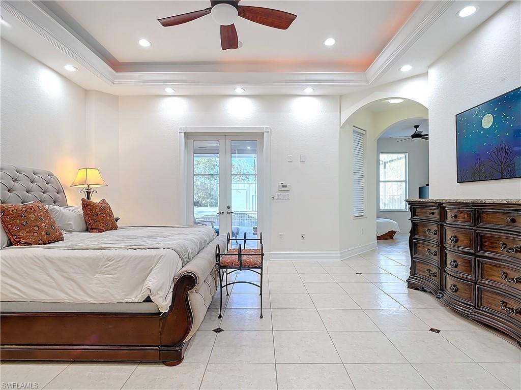 Bedroom with arched walkways, ceiling fan, ornamental molding, light tile patterned flooring, and recessed lighting