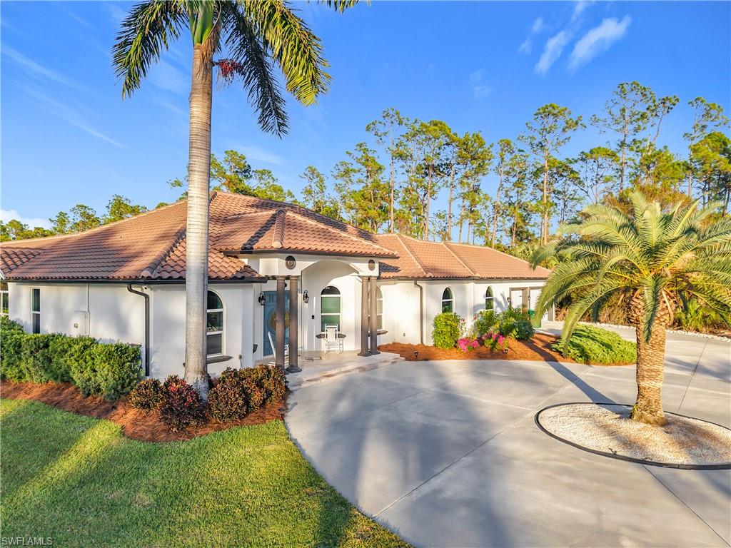 Mediterranean / spanish-style house featuring a tile roof, stucco siding, curved driveway, and a front lawn