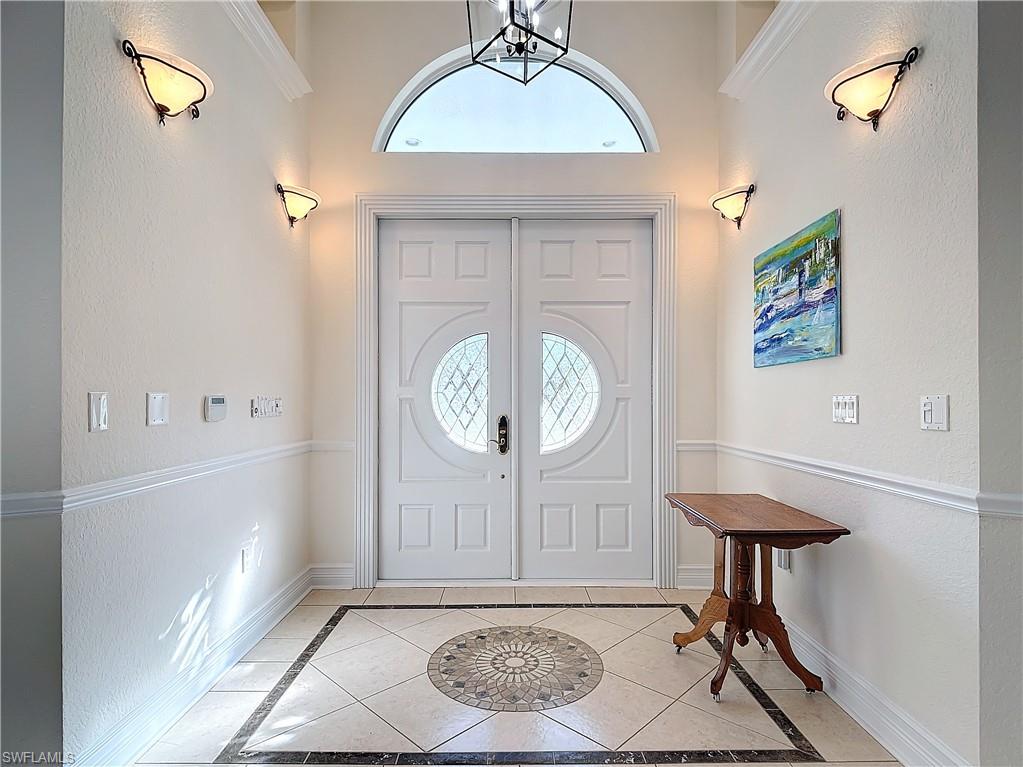 Foyer entrance featuring inlaid floor details, a textured wall, and light tile patterned floors