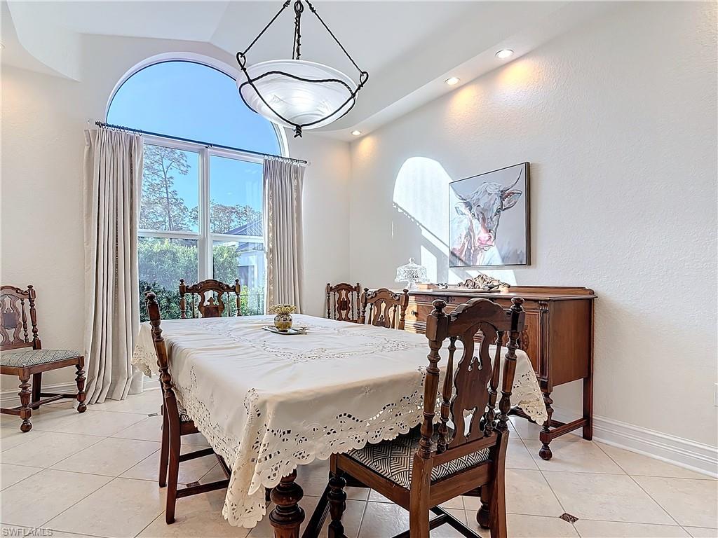 Dining area featuring light tile patterned floors, vaulted ceiling, a textured wall, and recessed lighting