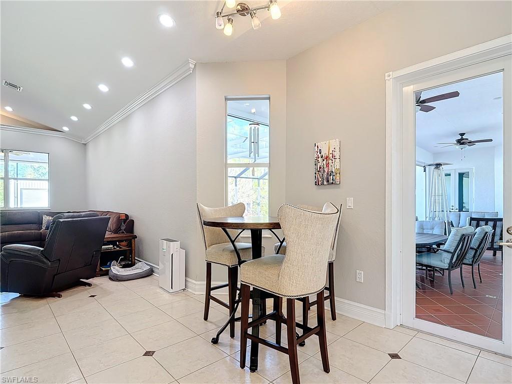 Dining room featuring light tile patterned floors, recessed lighting, a ceiling fan, lofted ceiling, and ornamental molding