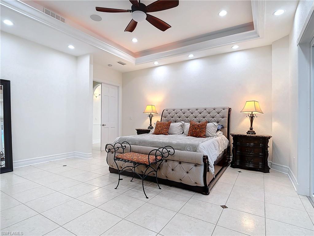 Bedroom with light tile patterned flooring, recessed lighting, a ceiling fan, and a tray ceiling