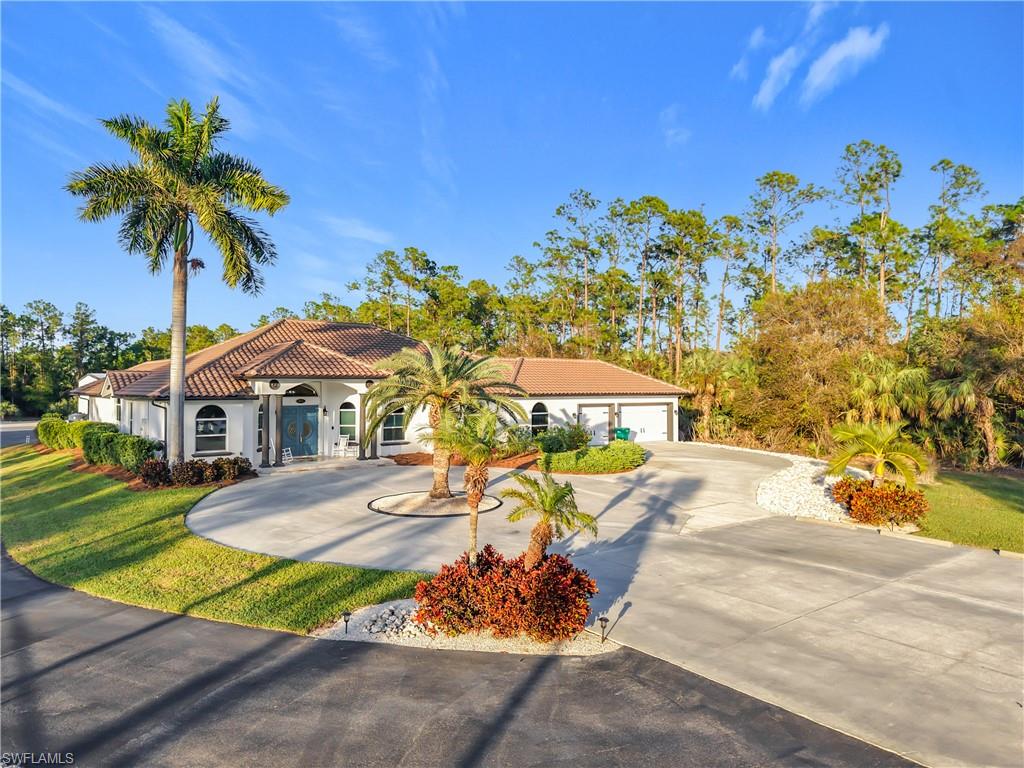 Mediterranean / spanish-style house with concrete driveway, a tiled roof, a front lawn, and stucco siding