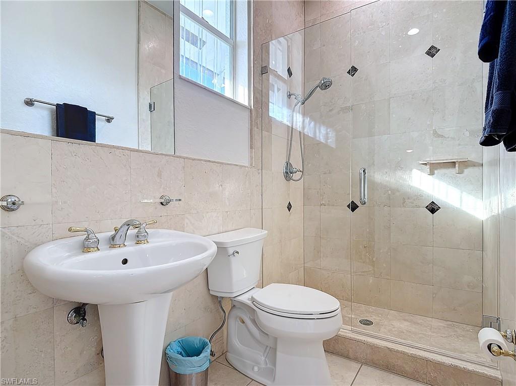 Full bathroom with tile walls, a shower stall, and tile patterned flooring