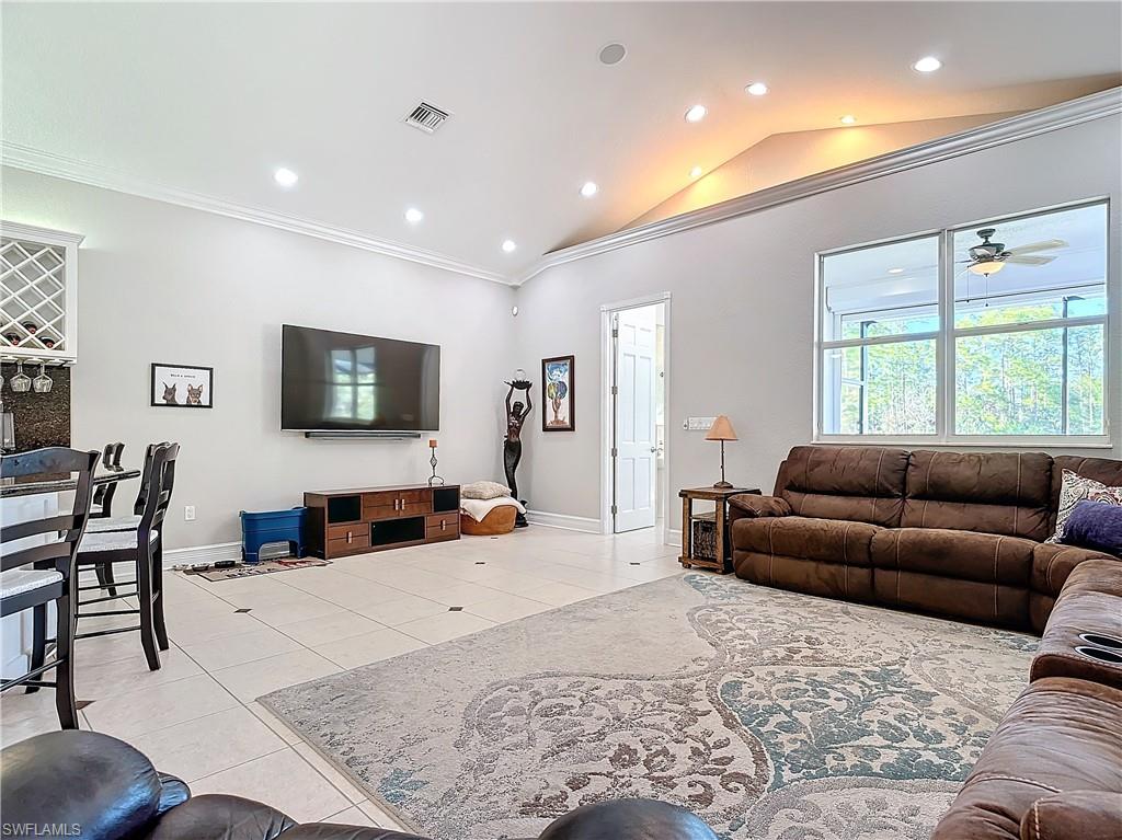 Living room with vaulted ceiling, ornamental molding, recessed lighting, light tile patterned flooring, and a ceiling fan