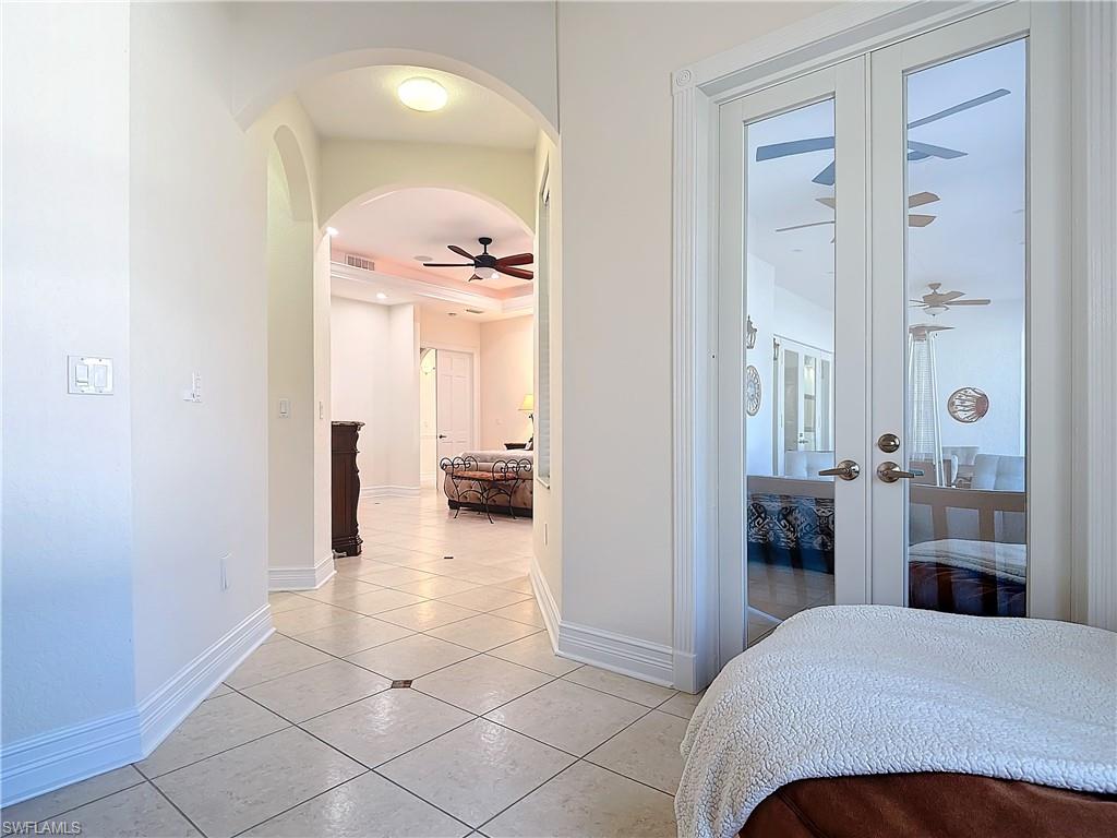 Bedroom featuring french doors, arched walkways, light tile patterned floors, and access to exterior
