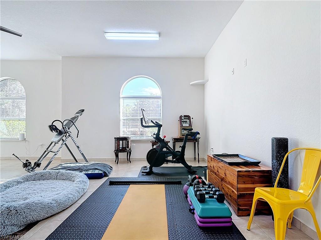 Exercise area featuring light tile patterned flooring and baseboards